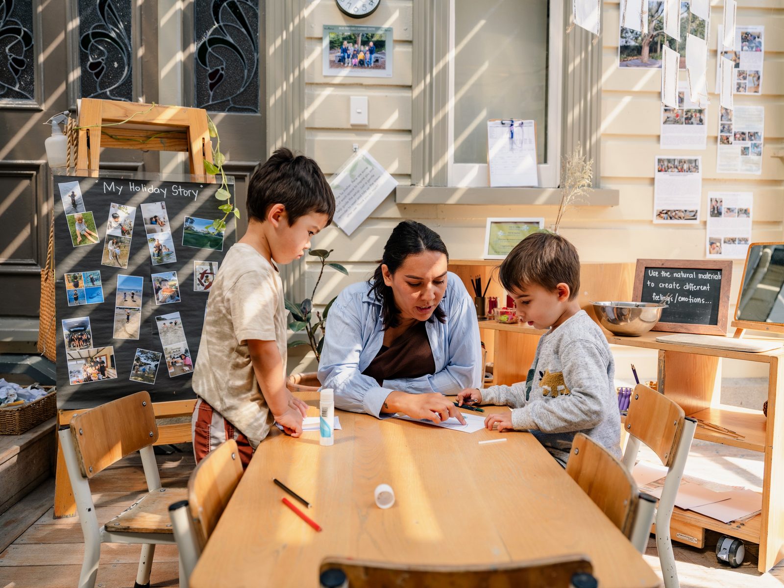 A teacher researching alongside children in a documentation-lined room
